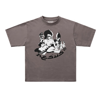 A short-sleeve crewneck t-shirt in a muted taupe-brown color, featuring a black and white graphic print of a seated figure with stylized text on the front, displayed flat against a light gray background.
